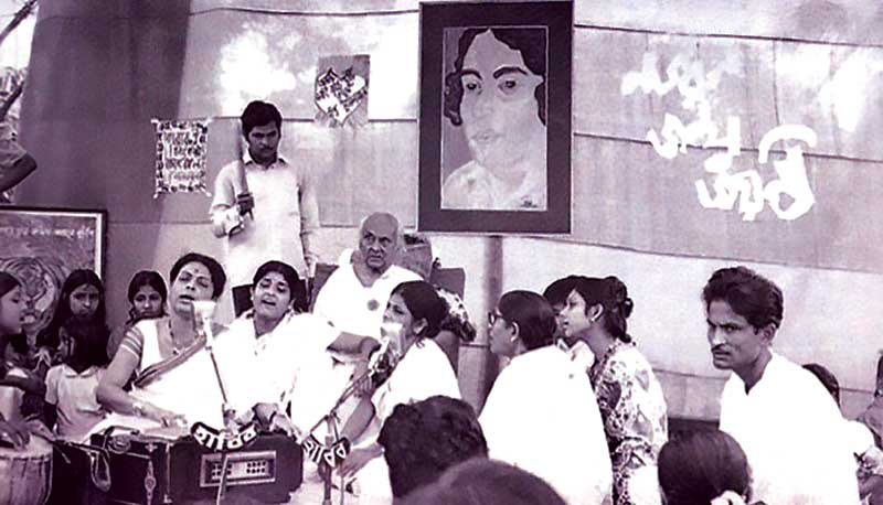 Kazi Nazrul Islam, sitting behind, on his 74th birthday listens to a song rendered by his family members along with Anjali Mukhopadhyay and Renu Bhowmick