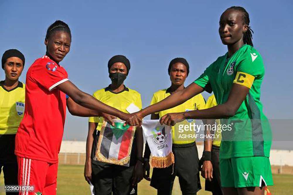 (L to R) The captains of Sudan and South Sudan shake hands before the start of a FIFA women's football friendly match between Sudan and South Sudan at Jebel Awliaa stadium in Sudan's capital Khartoum on February 16, 2022. - Sudan's women national team was officially created in 2021, around two years following the ouster of Islamist president Omar al-Bashir whose three-decade rule which saw little freedoms for women. The team has since took part of the Arab Women's Cup 2021 playing against Egypt, Tunisia, and Lebanon. They also played Algeria in October, and South Sudan this month.