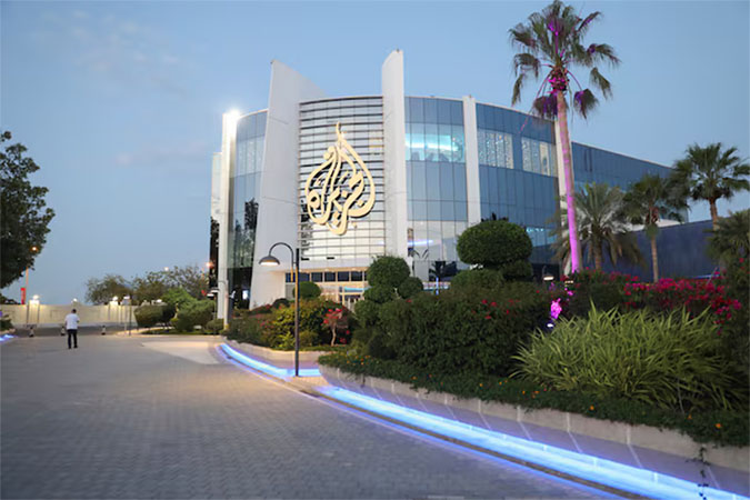 A man walks near an Al Jazeera building in Doha, Qatar, May 5, 2024. REUTERS/Arafat Barbakh/File Photo