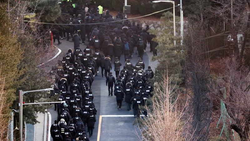 Police officers and investigators of the Corruption Investigation Office for High-ranking Officials pass through the entrance to the official residence of impeached President Yoonl, as authorities are seeking to execute an arrest warrant,