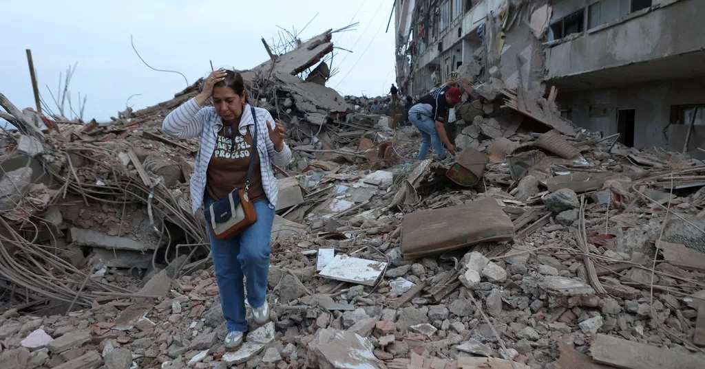 Residents walk among the rubble of building damaged in earthquakes the previous day in Venezuela’s Catia La Mar on Thursday. (AP Photo/Pedro Mattey)