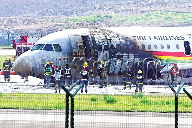 Firefighters check a plane which caught fire after veering off the runway 