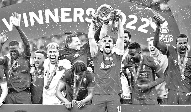 Liverpool's English midfielder Jordan Henderson (front R) holds the trophy as he celebrates with teammates after winning the English FA Cup final football match between Chelsea and Liverpool, at Wembley stadium, in London, on May 14, 2022.	photo: AFP 