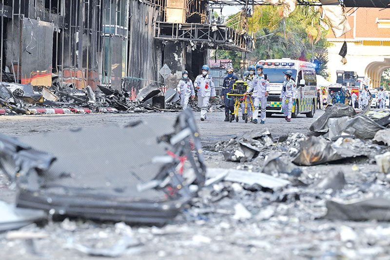 A paramedic team walks through a burned out part of the Grand Diamond City hotel-casino