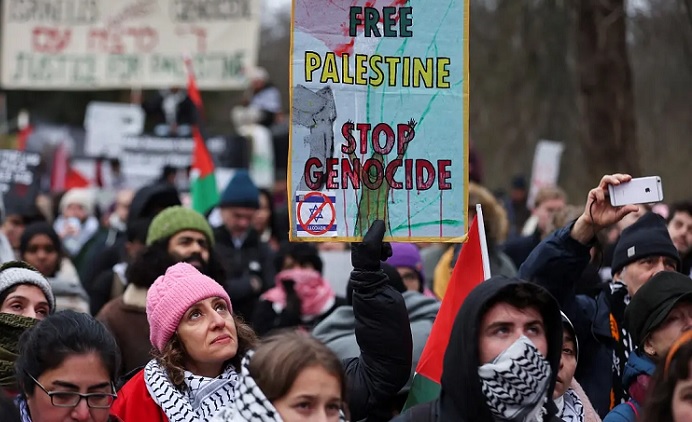 A pro-Palestinian demonstrator holds a placard during a protest near the International Court of Justice (ICJ) on the day judges hear a request for emergency measures to order Israel to stop its military actions in Gaza, in The Hague, Netherlands, on January 11, 2024. (Reuters)