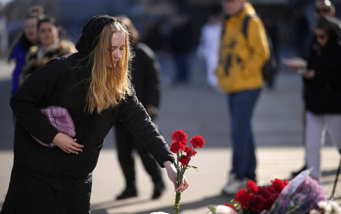 A woman places flowers at a makeshift memorial in front of the Crocus City Hall on the western outskirts of Moscow on Mar. 27, 2024. (AP)