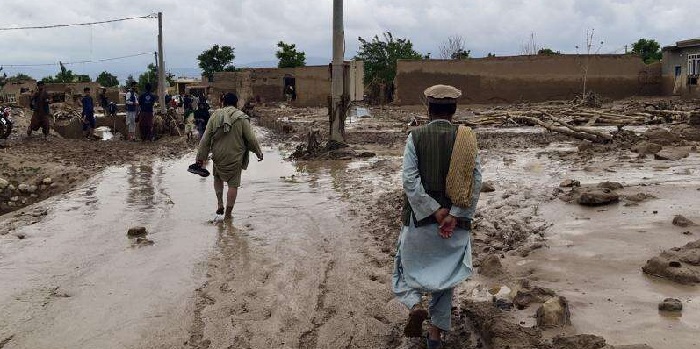 People are seen near to their damaged homes after heavy flooding in Baghlan province in northern Afghanistan Saturday, May 11, 2024. 