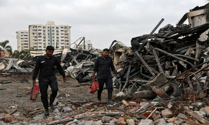 Firefighters carry hose pipes next to debris following a fire in a gaming zone in Rajkot, in the western state of Gujarat, India on May 26, 2024. — Reuters