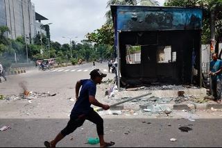 A police box was burnt in the capital. A protester runs by