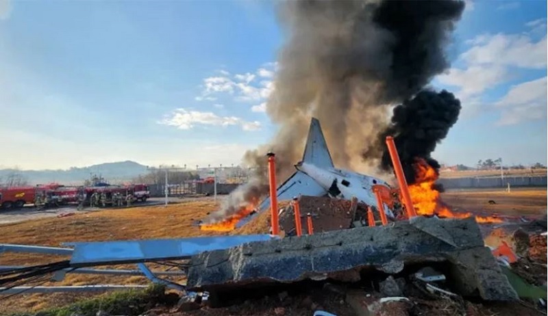 Fire and smoke rise from the tail section of a Jeju Air Boeing 737-800 series aircraft after the plane crashed and burst into flames at Muan International Airport 